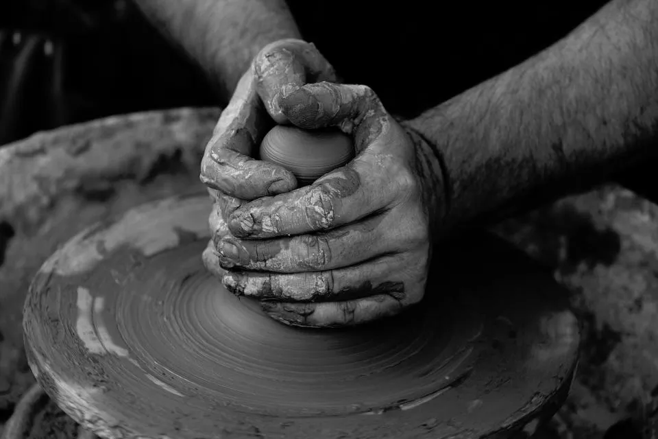 Potter's hands centring clay on a turning wheel
